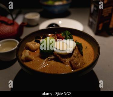 Un gros plan d'un bol de soupe de Ramen fraîche avec des œufs et des légumes Banque D'Images