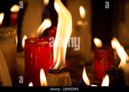 A closeup of big fire flames of candles in dark on a blurred background Stock Photo