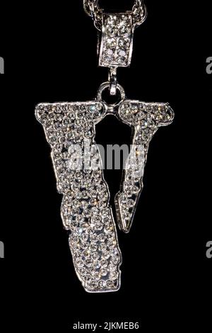 A Closeup of a white golden V letter on a chain necklace Banque D'Images