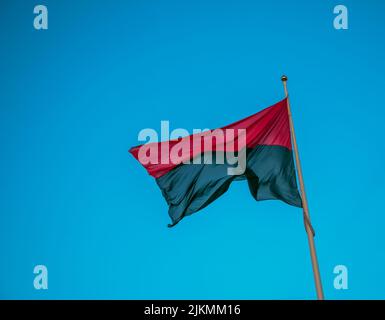 Drapeau rouge-noir des nationalistes ukrainiens, isolés sur fond bleu ciel, en gros plan. Fond de tissu de soie qui flottare dans l'air. Banque D'Images