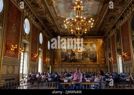 A beautiful shot of people having their meals in an adorned large hall with historical paintings in a restaurant in Dijon, France Stock Photo