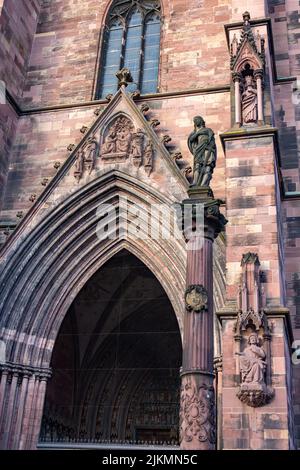 A vertical shot of the statue of the Virgin Mary and the detail of the main entrance of Freiburg Cathedral, Germany Stock Photo