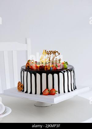Un gâteau au chocolat et à la fraise avec une affiche d'anniversaire sur une table blanche avec un fond blanc Banque D'Images