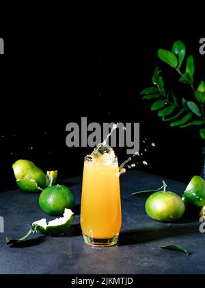 A vertical shot of the mandarin juice and green leaves Stock Photo