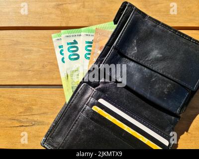 Portefeuille en cuir noir contenant plusieurs billets de 100 euros Banque D'Images