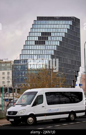 A parked transport van by a sidewalk with the Baltyk office building in the background Stock Photo