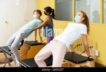 Adolescents dans les masques d'entraînement pilates dans la salle de gym avec traine Banque D'Images