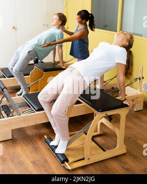 Adolescents d'entraînement pilates dans la salle de gym avec entraîneur Banque D'Images