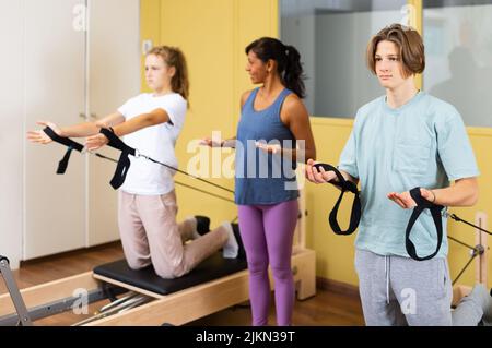 Adolescents d'entraînement pilates dans la salle de gym avec entraîneur Banque D'Images