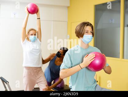 Adolescents dans les masques d'entraînement pilates dans la salle de gym avec entraîneur Banque D'Images