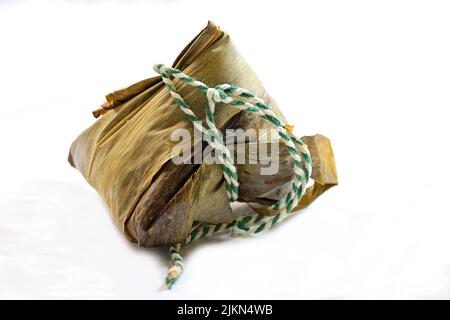 Un boulonnage chinois de riz collant, zongzi ou bakcang, enveloppé dans des feuilles de bambou, sur fond blanc Banque D'Images