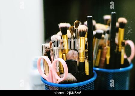 A closeup shot of a set of makeup brushes, scissors, and comb reflected on the mirror Stock Photo