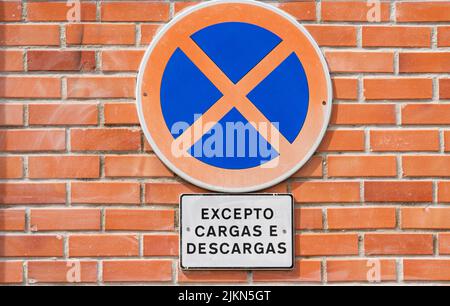 A closeup shot of 'No parking' sign posted on brick wall Stock Photo