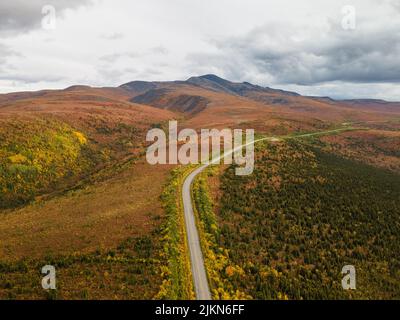 An aerial view of the Taylor Highway through lush greenery and Mount Fairplay in Alaska, USA Stock Photo