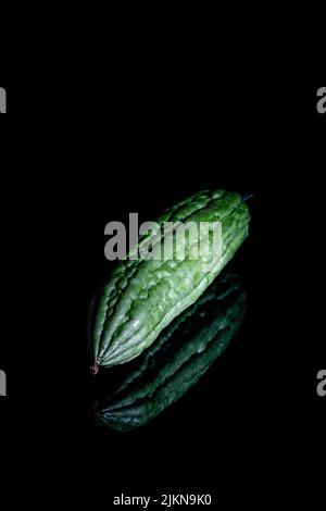 A vertical closeup shot of a bitter melon on a black background Stock Photo