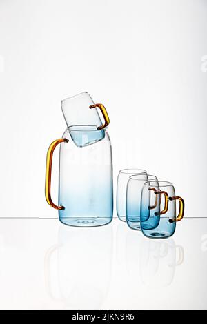 The vertical shot of a glass blue transparent  cups and juice pot with a white background Banque D'Images