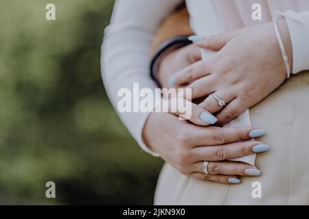 The husband hugging his pregnant wife's belly from the back in the park on a blurred background Banque D'Images