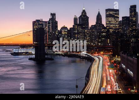 Le pont de Brooklyn au-dessus des belles couleurs du coucher du soleil et les lumières des grands gratte-ciel, New York Banque D'Images