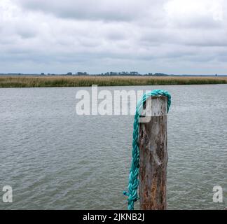 The Old wooden pier with brown rope and bollard on the sea horizon near the harbor. Stock Photo