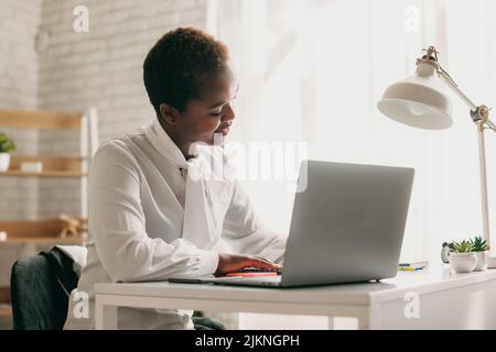 Étudiant noir, rédaction de notes, regarder un webinaire sur un ordinateur portable, étudier en ligne. Assister à une réunion d'affaires virtuelle. Séminaire. Banque D'Images