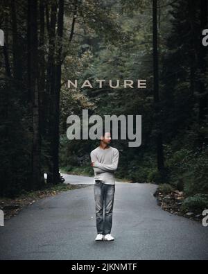 Un cliché vertical d'un homme debout dans la rue dans la forêt avec la « nature » sur lui Banque D'Images