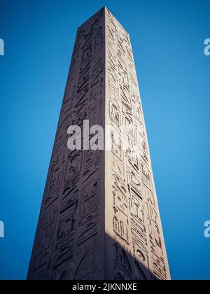 A vertical low angle shot of a tall historic obelisk with carvings in the Mortuary Temple of Hatshepsut Stock Photo