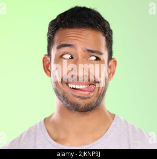 HES un peu incertain. Un beau jeune homme faisant un visage sur un fond vert en studio. Banque D'Images