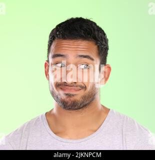 Ne Regarde-moi. pas un beau jeune homme qui fait un visage sur fond vert en studio. Banque D'Images