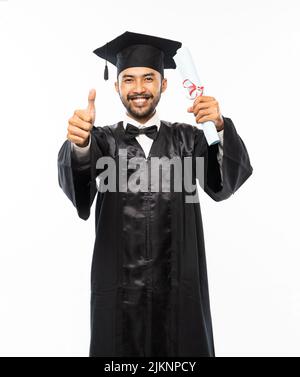 Homme excité portant tosa avec les pouces vers le haut tenant le papier de diplôme Banque D'Images