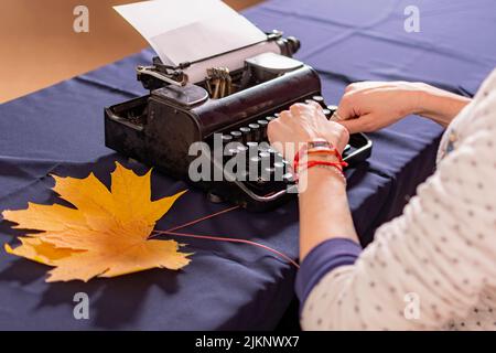 Les mains de la jeune fille sont en train de taper sur une vieille machine à écrire. Un employé de bureau est engagé dans le travail de secrétaire. Banque D'Images