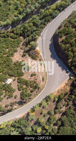 A vertical aerial shot of an asphalt road passing through a forested area Stock Photo