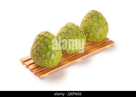 A closeup shot of three artichokes on a wooden board isolated on a white background Stock Photo