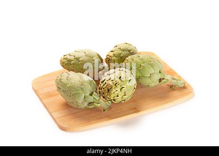 A closeup shot of five artichokes on a wooden board isolated on a white background Stock Photo