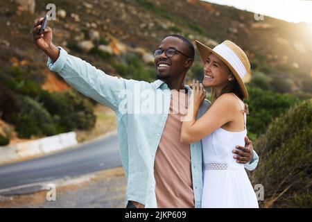 Plus nous voyageons, plus nous gagnons de souvenirs. Un jeune couple heureux qui prend des selfies en voyage. Banque D'Images