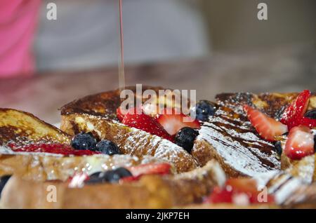 A closeup shot of french toasts with blueberries and strawberries and some honey on top Stock Photo