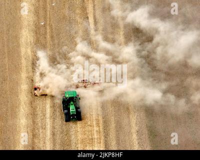 Un agriculteur de son tracteur John Deere, avec des chenilles caterpillar, fait monter la poussière en travaillant sur son champ près de Wisbech, Cambridgeshire. Banque D'Images