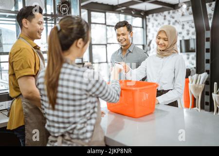 Femme en voile donne la carte de crédit pendant le paiement à la caissière Banque D'Images