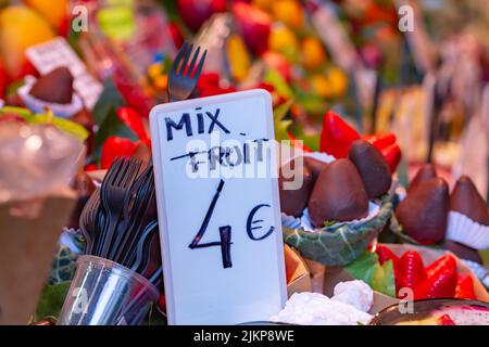 Different types of assorted fruit with selective approach to the poster, with plastic cup and fork at the Boqueria market in Barcelona (Spain). Banque D'Images