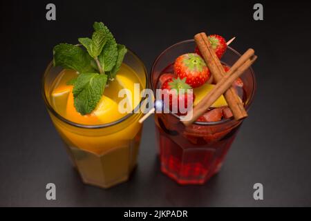 A high-angle shot of two glass cups of fancy and tasty fruit cocktails on a dark background Banque D'Images