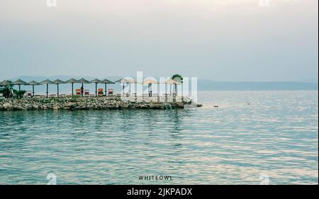 A scenic view of folding chairs and umbrellas on the beach in the blue sky background Stock Photo