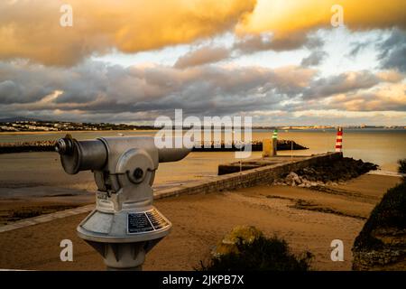 A mesmerizing sunset view of the sea with a telescope on the foreground in Lagos, Praia Da Luz Stock Photo