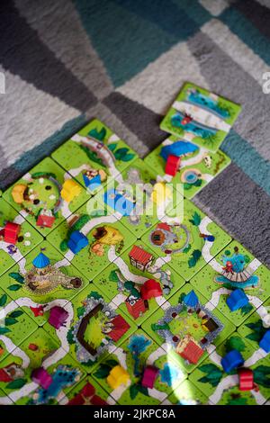 Un cliché vertical d'un jeu de Carcassonne Junior avec des cartes et des figurines en bois colorées sur un sol de tapis. Banque D'Images