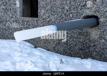 Un tuyau d'eau dans une maison avec un morceau de glace congelé. Récolte de l'eau de pluie Banque D'Images