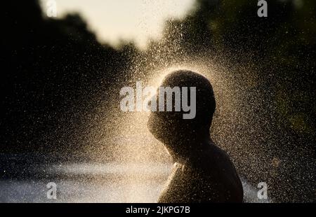 Hanovre, Allemagne. 03rd août 2022. Un homme prend une douche tôt le matin dans la piscine extérieure d'Annabad à la lumière du soleil levant. Credit: Julian Stratenschulte/dpa/Alay Live News Banque D'Images