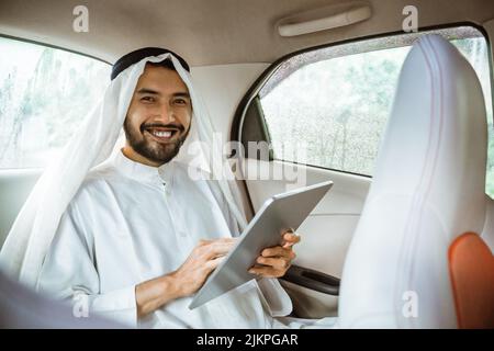 homme portant le turban à l'aide d'un coussin alors qu'il est assis sur sa voiture Banque D'Images