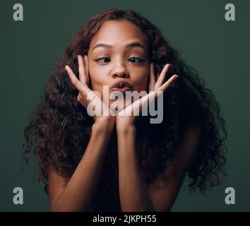 Baiser moi fou. Portrait court d'une jeune femme attrayante et originale se posant sur un fond vert en studio. Banque D'Images