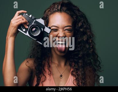 Souriez. Portrait court d'une jeune femme attrayante et originale se posant sur un fond vert en studio. Banque D'Images