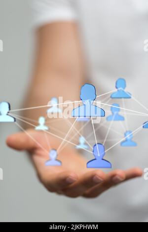 A vertical 3d rendering of human figures in blue connected with neural networks floating above a hand Stock Photo