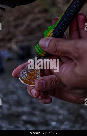 A vertical shot of man is holding a small jar and a tube of cannabis oil in his hands Stock Photo