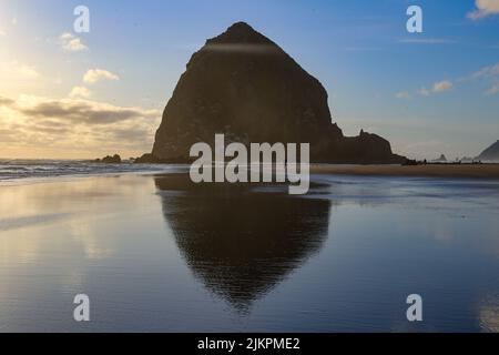 Scenic Haystack Rock in Cannon Beach reflected on the water surface, Oregon, United States Stock Photo